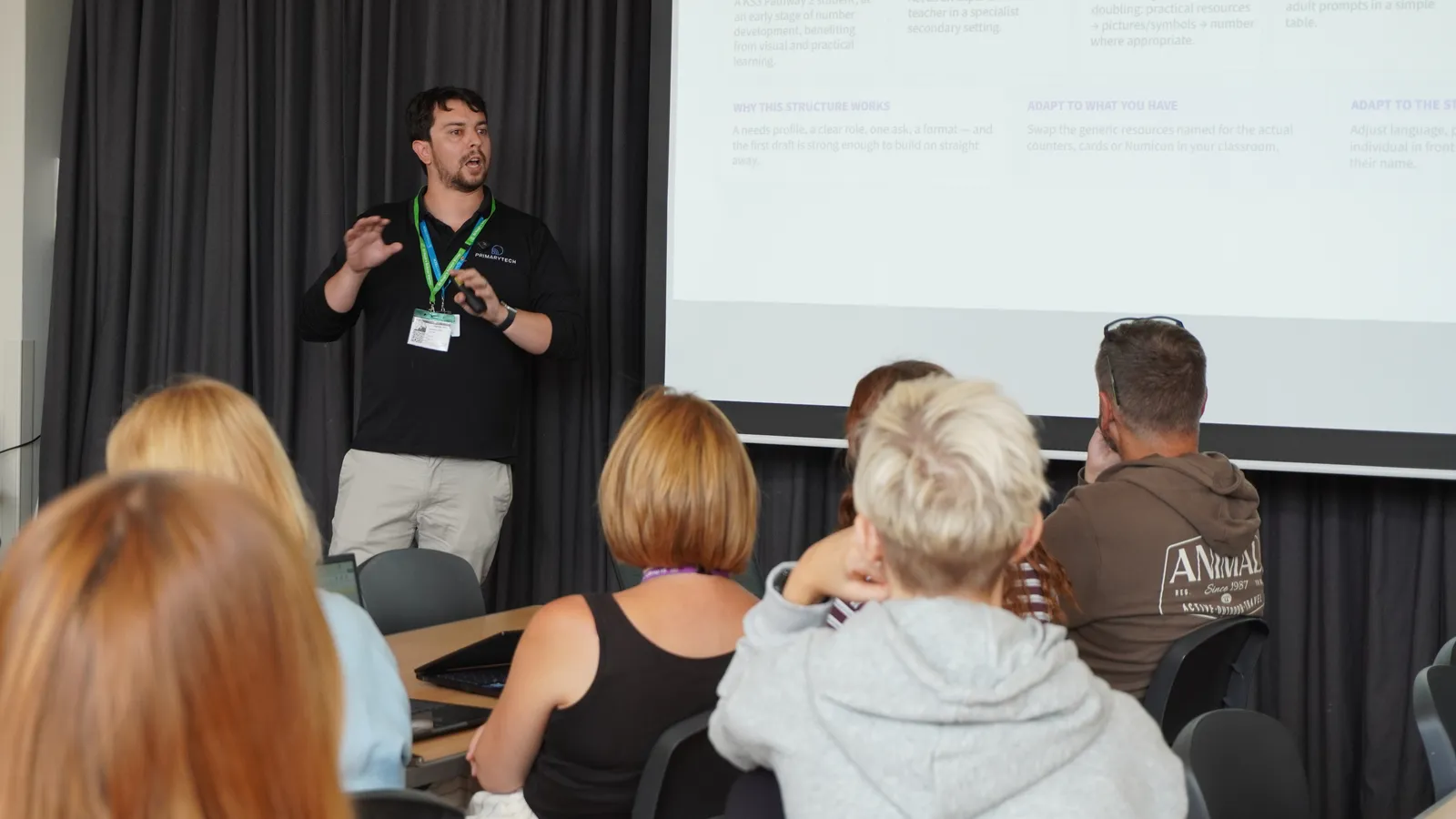 Devin, digital transformation lead, delivering INSET day training at a local school with teachers sat down watching him talk next to an interactive screen