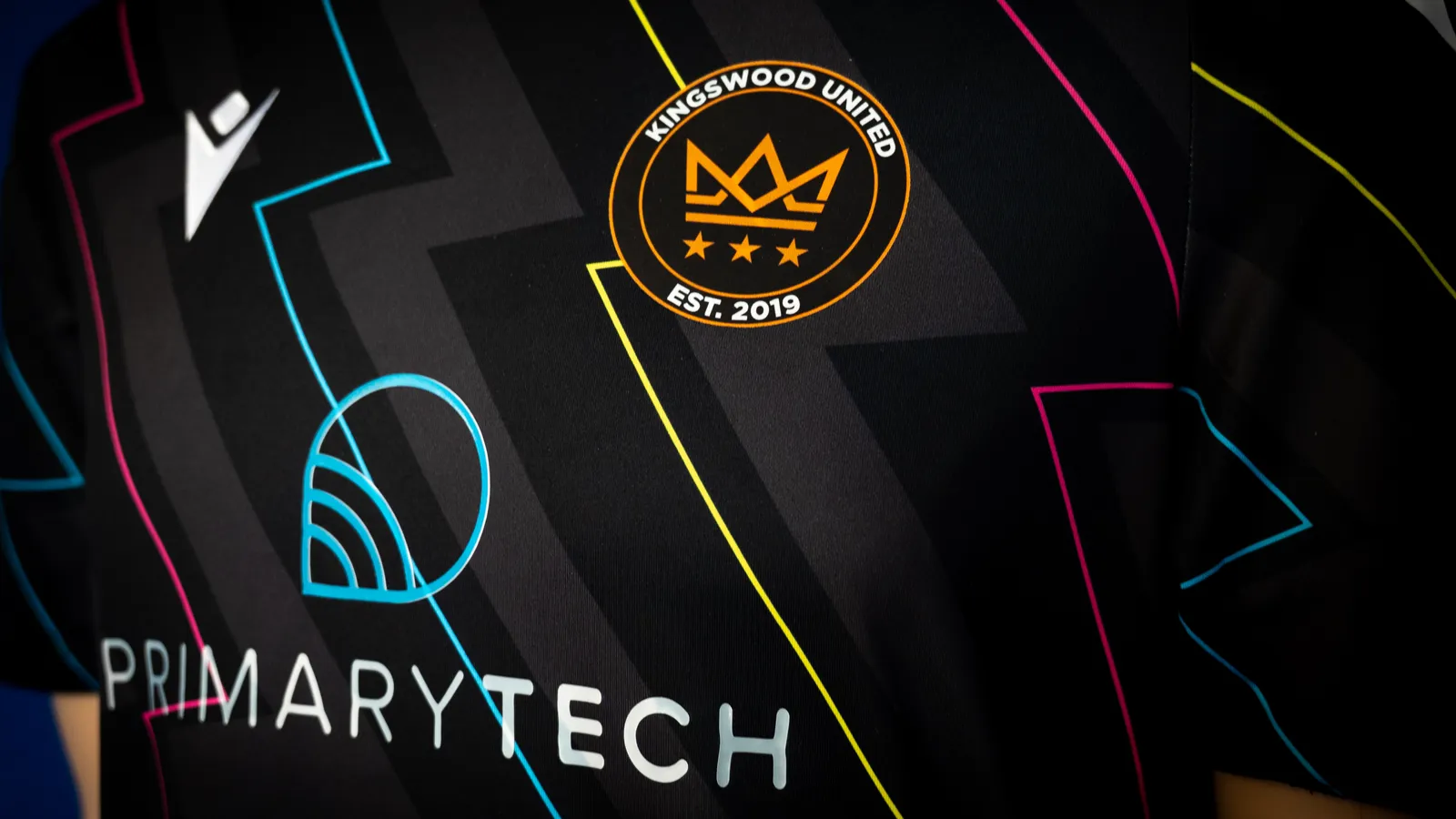 Black football top featuring kingswood united crown badge and primarytech logo who are the platinum sponsor