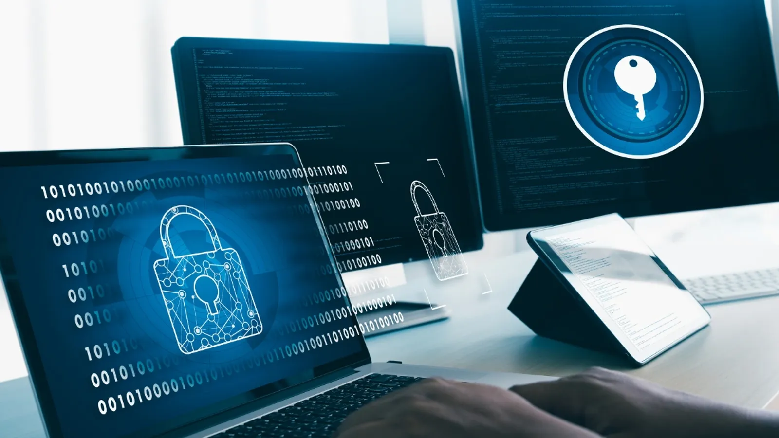 Laptop and monitors displaying binary code and padlock graphics, representing antivirus and data encryption